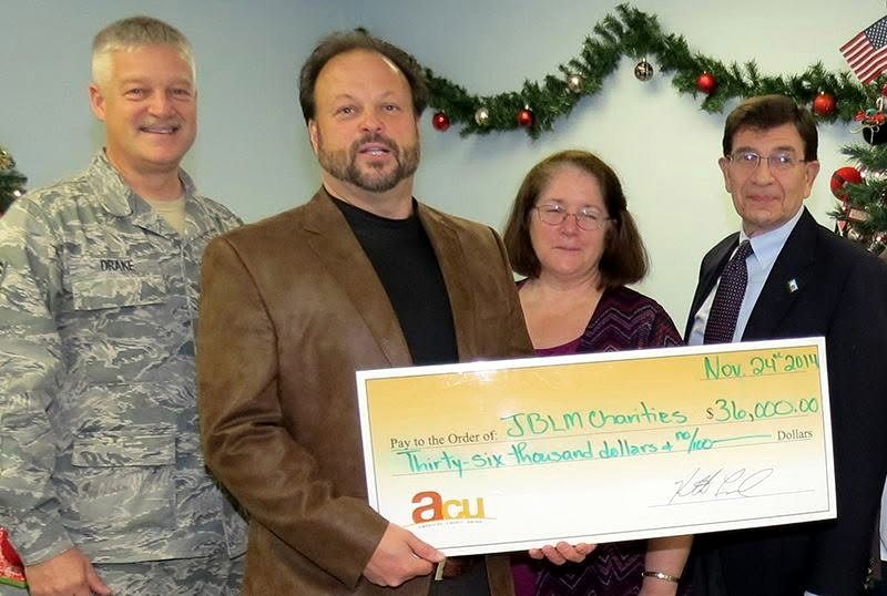 Ken Leonard and three community partners hold a check to JBLM Charities dated November 24, 2011