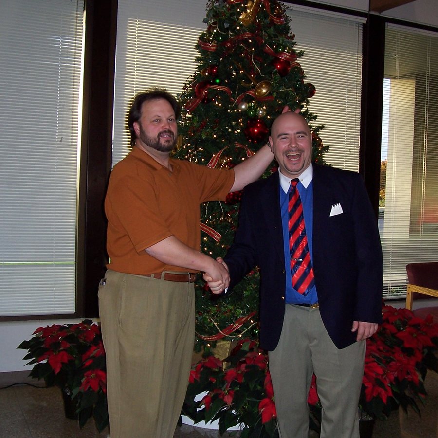 Ken Leonard sharing a laugh with a colleague beside a holiday tree in a branch lobby