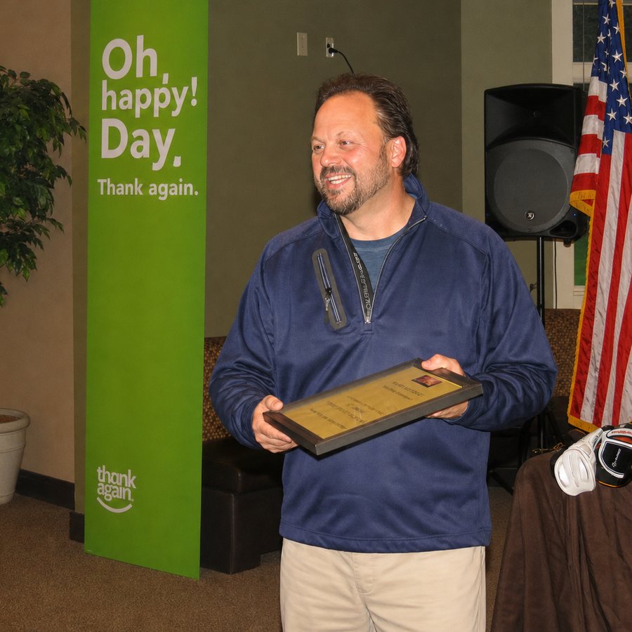 Ken Leonard holding a recognition plaque at a member appreciation event