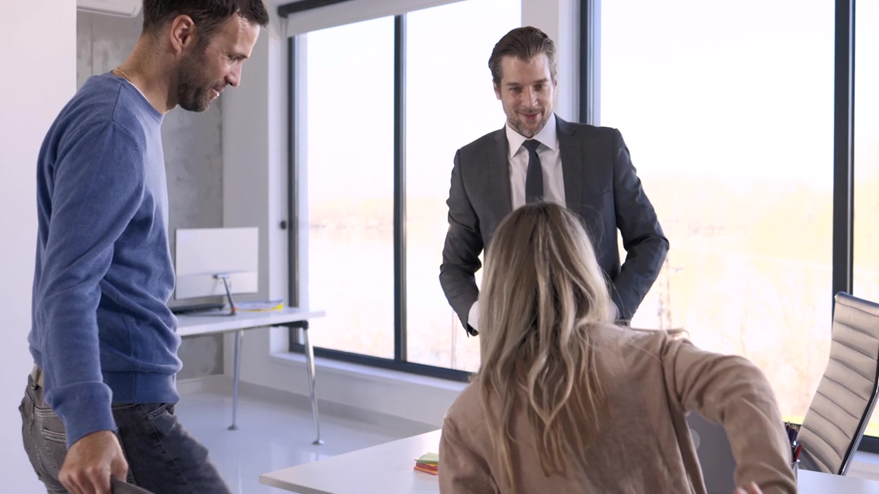 Consultant welcoming clients to a meeting in a bright office
