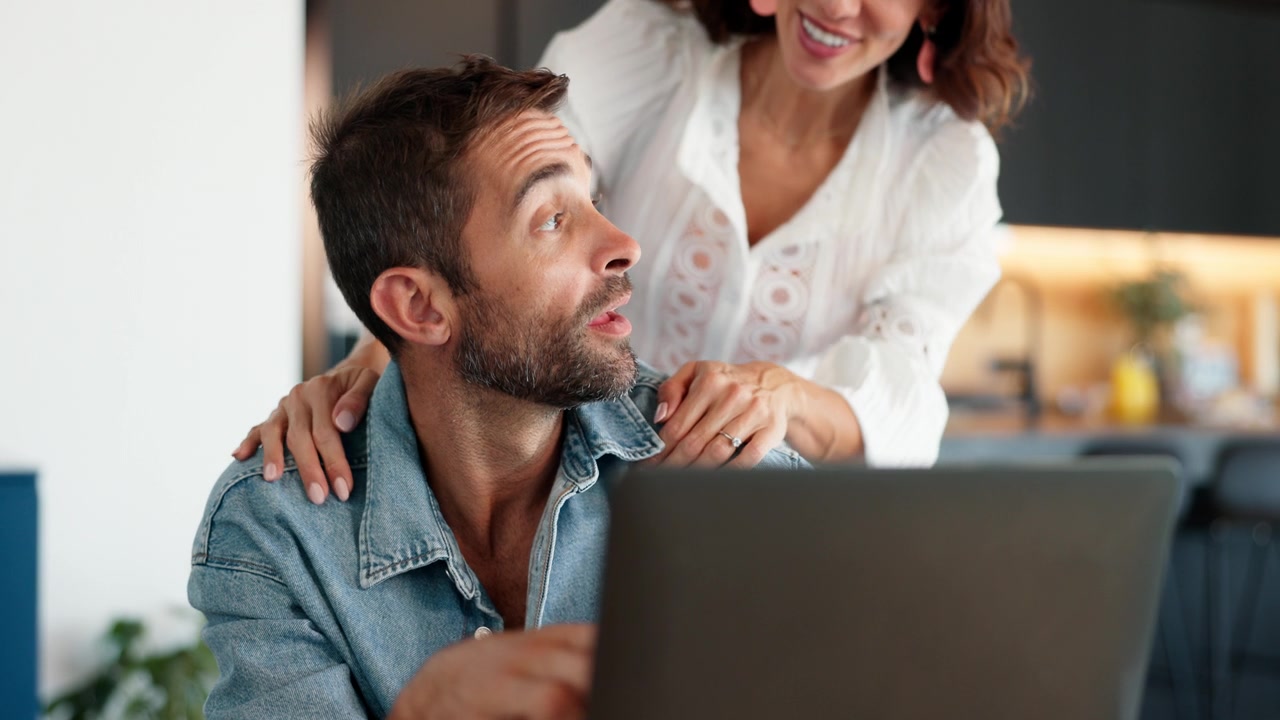Couple celebrating a loan approval on their laptop at home