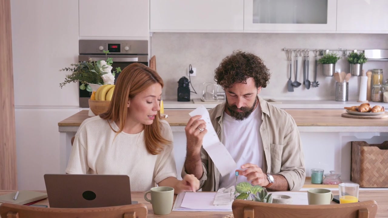 Couple reviewing bills and statements at their kitchen table
