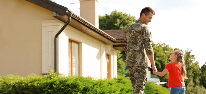 A soldier and his daughter standing outside the home he bought by taking advantage of the benefits of a VA loan.