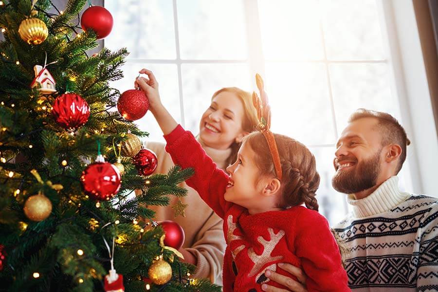 A family decorates a tree using funds from a a Christmas Club Account.