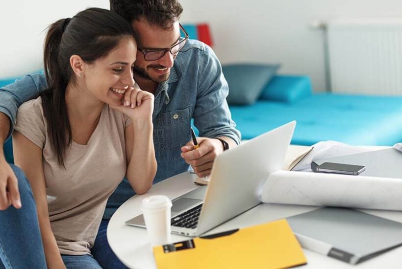 A happy couple smiling as they check their Regular Shared Savings account balance online.