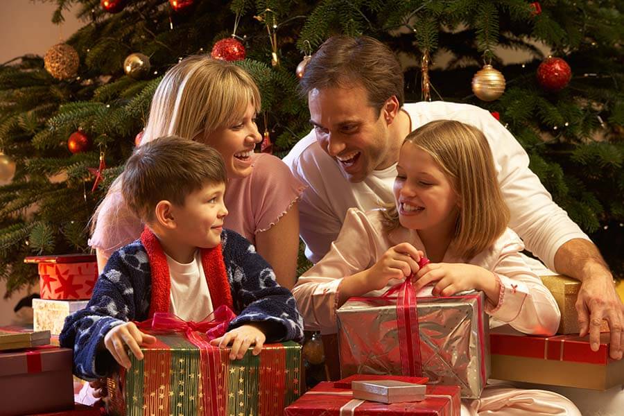 A family opens presents in front of the Christmas tree.