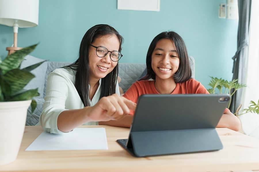 A mother showing her teenage daughter how to use her teen savings account.