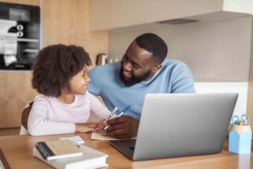 A parent showing his daughter how to save money using her kids' savings account.