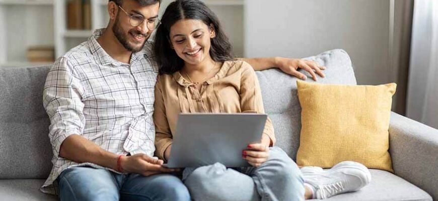 A young couple easily opens a checking account online from the comfort of their home.